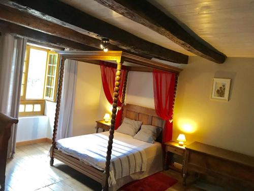 a bedroom with a canopy bed with red curtains at Le moulin de preuillé in Valence en Poitoux