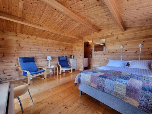 a bedroom with a bed and two chairs and a table at Kaggestorps Gård in Hjo