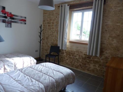 a bedroom with a bed and a window and a chair at Les pierres de la dive in Valence en Poitoux
