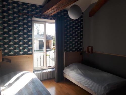 a bedroom with a window with blue and white wallpaper at Les saules in Persac