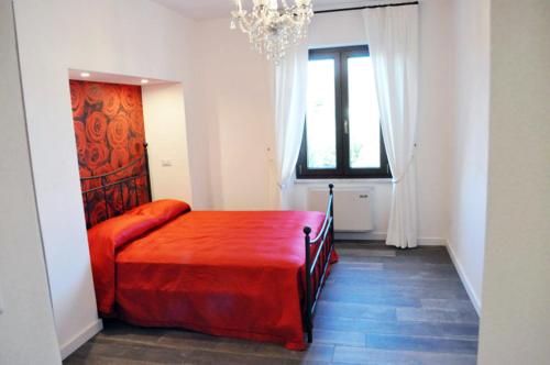 a bedroom with a red bed and a window at Casa Remussi in Treiso
