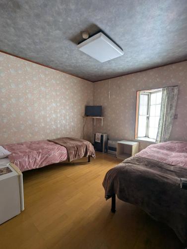a bedroom with two beds and a ceiling fan at Hachiko Inn in Myoko