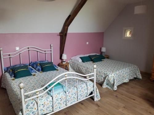 two beds in a bedroom with pink and purple walls at La maison de gatienne in Coussay-les-Bois