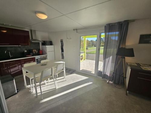 a kitchen with a white table and chairs and a door at Le pic epeiche in Saulgé