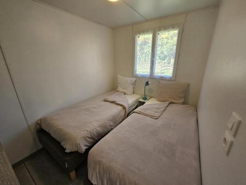 two beds in a small room with a window at Le pic epeiche in Saulgé