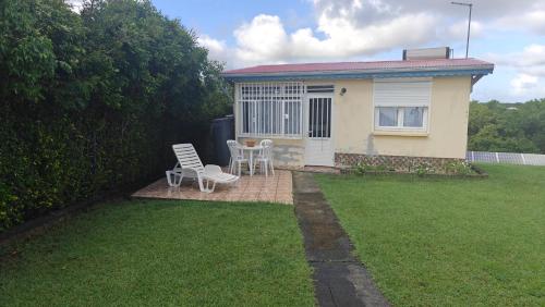 a house with a table and a chair in a yard at Cocooning sur mer Bungalow in Sainte-Anne