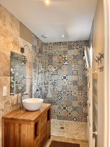 a bathroom with a sink and a mosaic wall at Le chant du jau in Beaumont