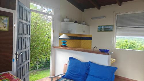 a living room with a blue couch and a window at Cocooning sur mer Bungalow in Sainte-Anne