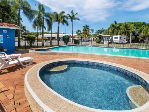 a swimming pool in a resort with palm trees at BIG4 Townsville Gateway Holiday Park in Townsville