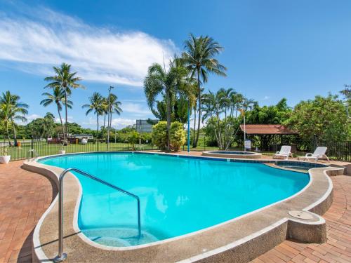 a swimming pool at a resort with palm trees at BIG4 Townsville Gateway Holiday Park in Townsville