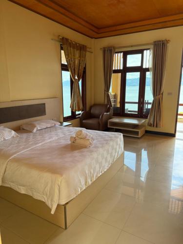 a bedroom with a bed and a chair in a room at Mas Cottages in Tuktuk Siadong