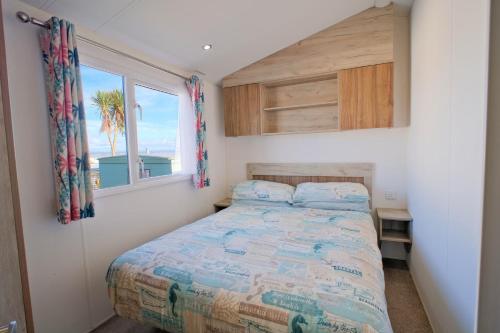 a small bedroom with a bed and a window at Sirocco Caravan in Westward Ho