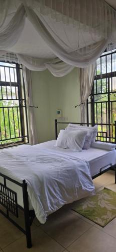 a bedroom with a bed with white sheets and windows at Greenhome apartment in Poli