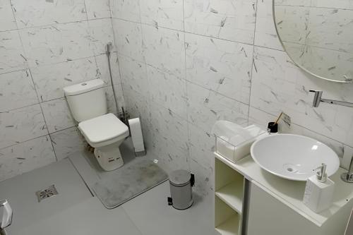 a white bathroom with a toilet and a sink at Coloft - Hospedagem e Coworking in Anápolis