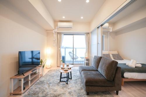 a bedroom with a bed and a couch and a tv at AYA Residence大阪城公園 Osaka Castle JR Morinomiya 徒歩5min in Osaka