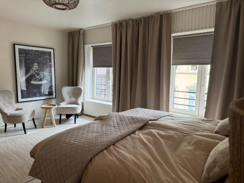 a bedroom with a bed and two chairs and windows at vakantie appartement D'vine in Valkenburg