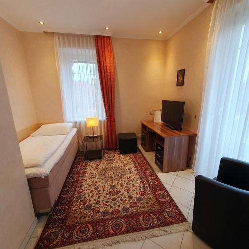 a bedroom with a bed and a desk and a television at Hotel Hotwagner in Maria Enzersdorf