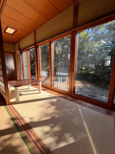 a screened in porch with windows and a bench at 古民家ゲストハウスときわ in Kamakura