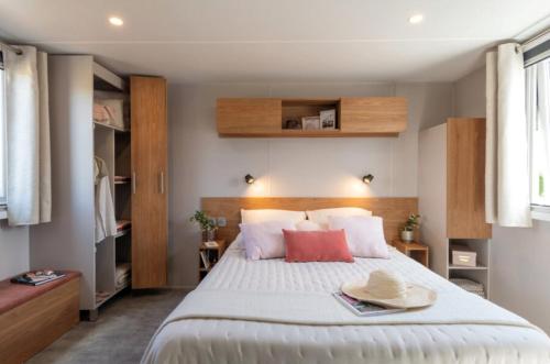 a bedroom with a large white bed with two red pillows at Camping le Héron in Dolus-d'Oléron
