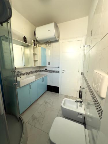 a white bathroom with a sink and a toilet at Sea View Apartment in Durrës