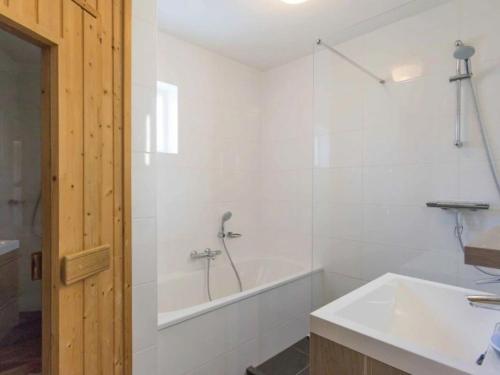 a white bathroom with a tub and a sink at Christoffellaan 101 in Brouwershaven