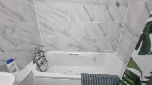 a white bath tub in a bathroom with marble walls at Extra Large One Bedroom Flat with Parking in London