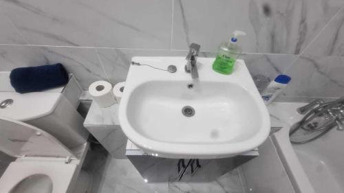 a white bathroom with a sink and a toilet at Extra Large One Bedroom Flat with Parking in London