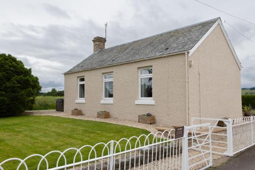 a house with a white fence in front of it at Bachilton Farm Holidays in Perth