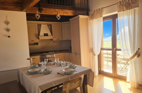 a kitchen with a table with plates and wine glasses at Attico e super attico panoramico in Rocca di Cambio