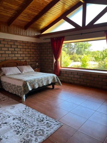 a bedroom with a bed and a large window at Casa Quinta el Labrador Renaico in Estación Roblería