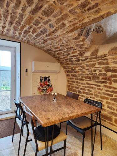a dining room with a stone wall and a table and chairs at Gîte de Burgy in Burgy