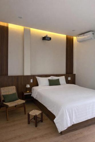 a bedroom with a large white bed and a chair at 19 home in Hue