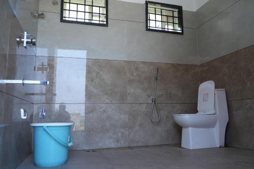 a bathroom with a toilet and a shower and a trash can at Aqua Terra Villas in Belūr