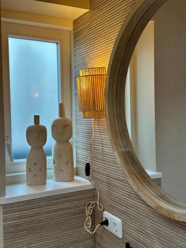 a bathroom with a mirror and two wooden figures on a counter at Studio Oranje Nassau aan Zee in Zandvoort