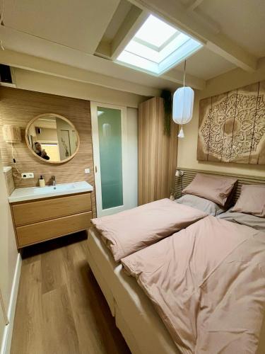 a bedroom with a bed and a sink and a mirror at Studio Oranje Nassau aan Zee in Zandvoort