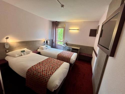 ein Hotelzimmer mit zwei Betten und einem Flachbildfernseher in der Unterkunft Brit Hotel Les Evens in Saint-Saturnin
