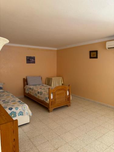 a bedroom with two beds and a chair in it at Cosy Apparemment in Nabeul