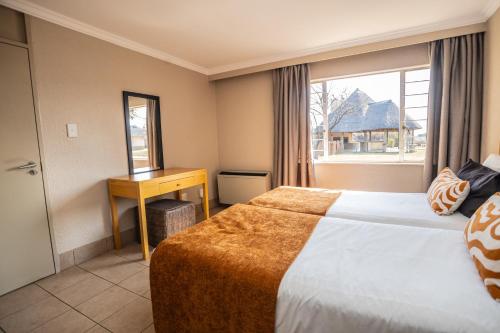a hotel room with a bed and a desk and a window at Carousel Eco Estate in Temba