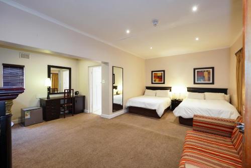 a hotel room with two beds and a couch at Cumberland Hotel & Conference Centre Worcester in Worcester