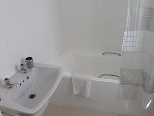 a white bathroom with a sink and a bath tub at Loader Street Cottage in Cape Town