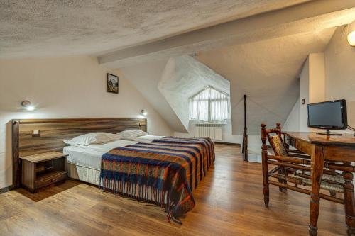 a bedroom with a bed and a desk and a television at Ema Hotel Bansko in Bansko