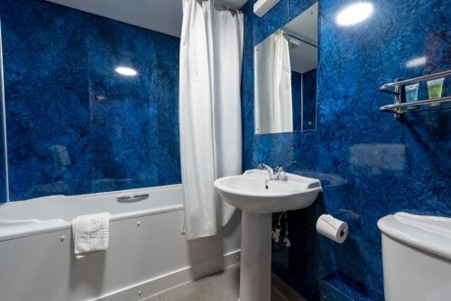a blue bathroom with a sink and a tub and a toilet at The Dog and Partridge in Langsett