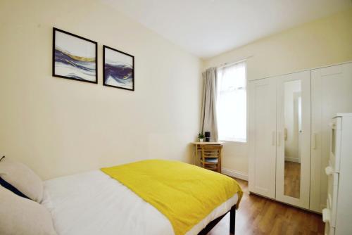 a bedroom with a bed with a yellow blanket on it at The Green Garden House near Tottenham Stadium Alexandra Palace Finsbury P in London
