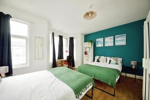 a bedroom with two beds and a blue wall at The Green Garden House near Tottenham Stadium Alexandra Palace Finsbury P in London