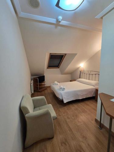 a bedroom with a bed and a chair and a table at HOTEL EL ROBLE PALENTINO in Cervera de Pisuerga