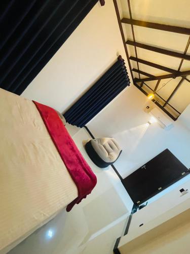 a room with a bed with a red blanket and a chair at Woori House in Kamburugamuwa