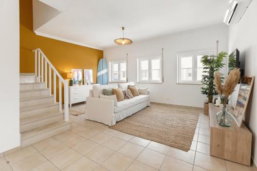 a living room with a white couch and a staircase at Casa da Shaka Baleal in Ferrel