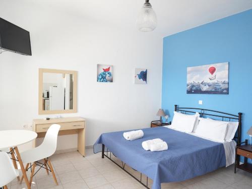 a blue and white bedroom with a bed and a table at Votsalo in Kardamaina