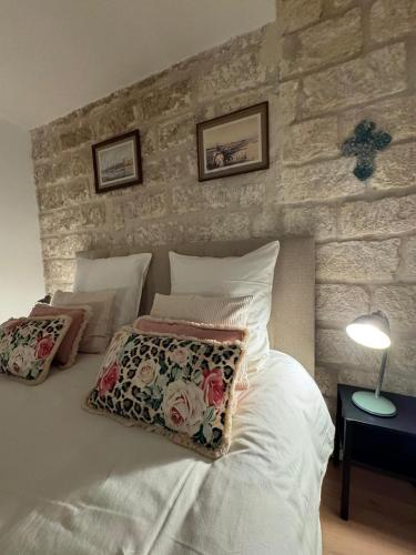 a bedroom with a white bed with a stone wall at Chez Marie & Nico in Aigues-Mortes