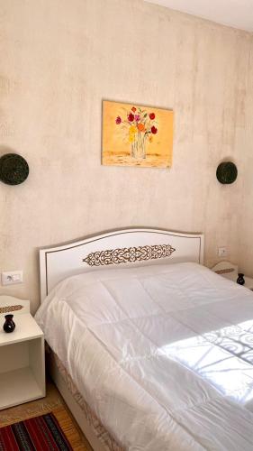 a bedroom with a white bed with a vase of flowers at Maison Bohème Suite Fatima in Midoun